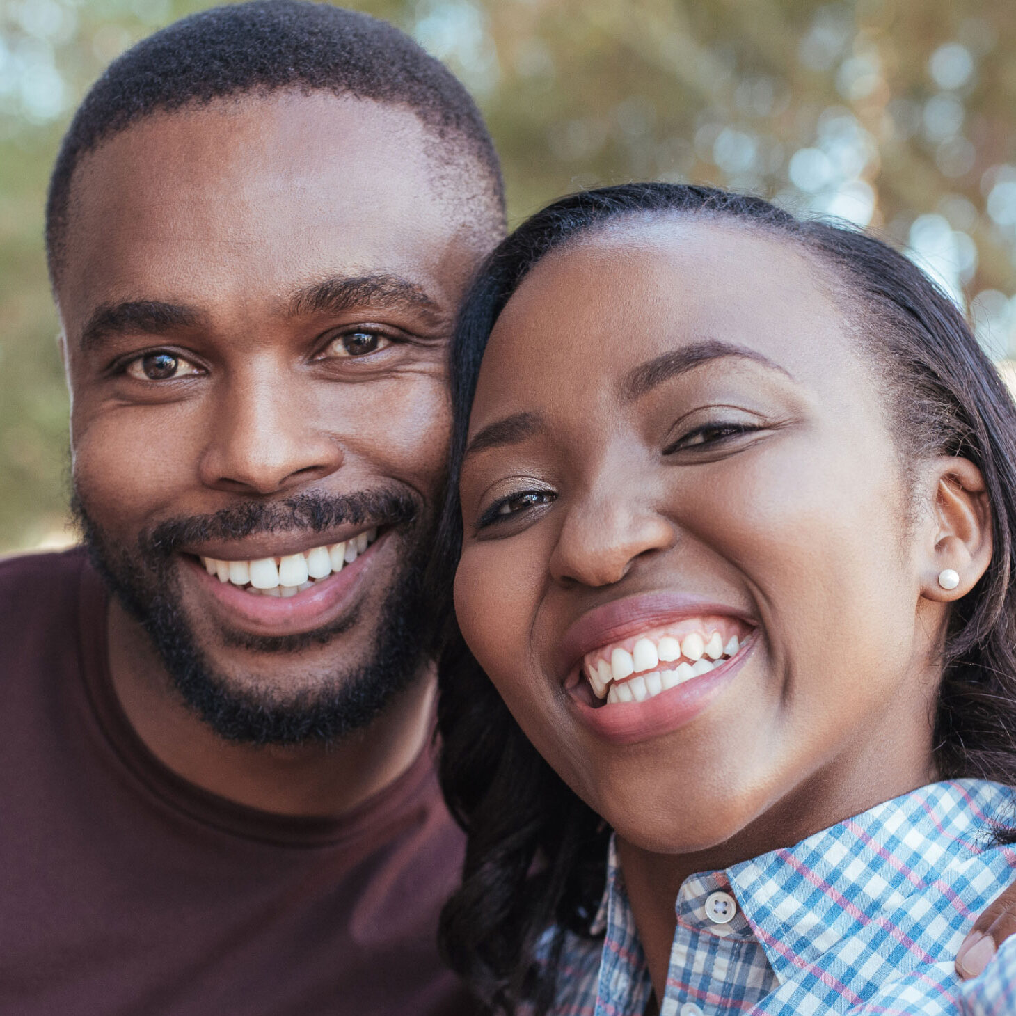 young african american couple hugging and taking a selfie in the park